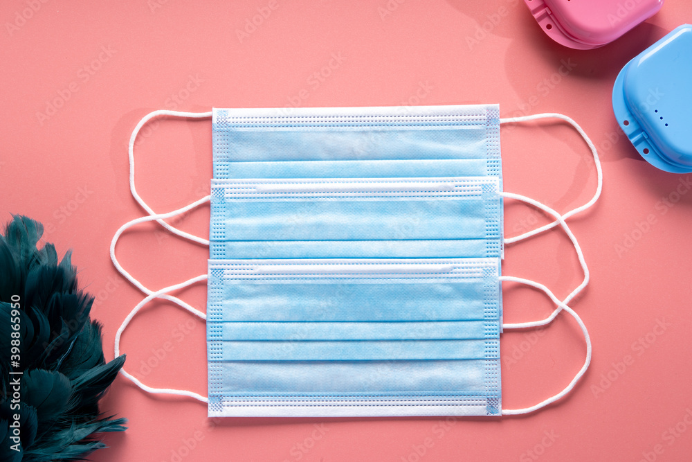 Mascarilla quirúrgica sobre fondo rosa con elementos azules muy juvenil y creativa composición de objetos de protección Mascarilla quirúrgica sobre fondo rosa con elementos azules muy juvenil y creativa composición de objetos de protección