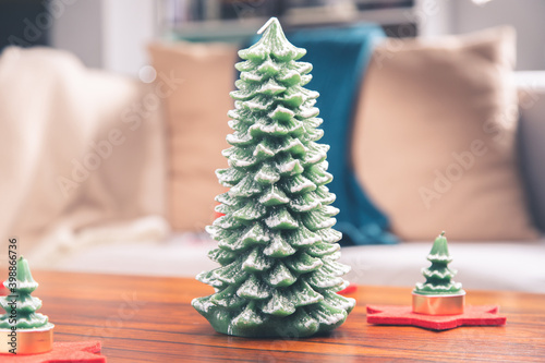 Vela navideña con forma de pino de Navidad sobre bonita mesa de madera y palisandro en un hogar de familia photo