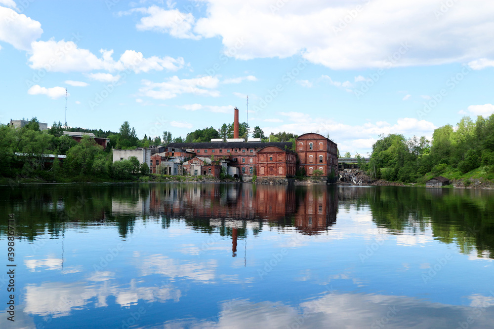 old abandoned paper factory made from red brick on the river shore with beautiful reflection