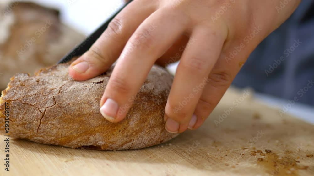 Female hands slicing bread on a cutting board Female hands slicing bread on a cutting board