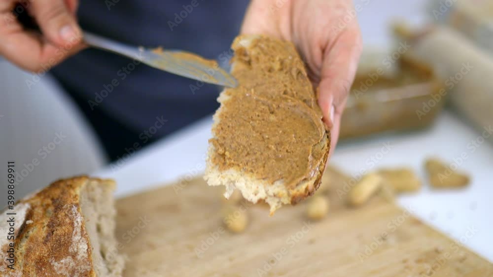 Female hands spreading peanut butter on a slice of bread Female hands spreading peanut butter on a slice of bread