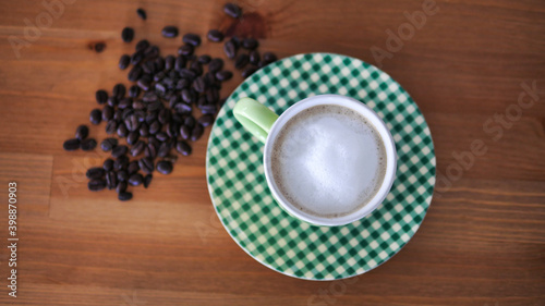 Top view a green cup of hot latte with frothy foam and coffee bean on wood background
