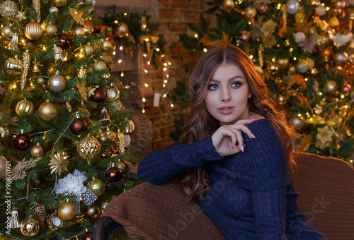 Young beautiful girl with loose hair close up sitting at the Christmas tree with Christmas toys