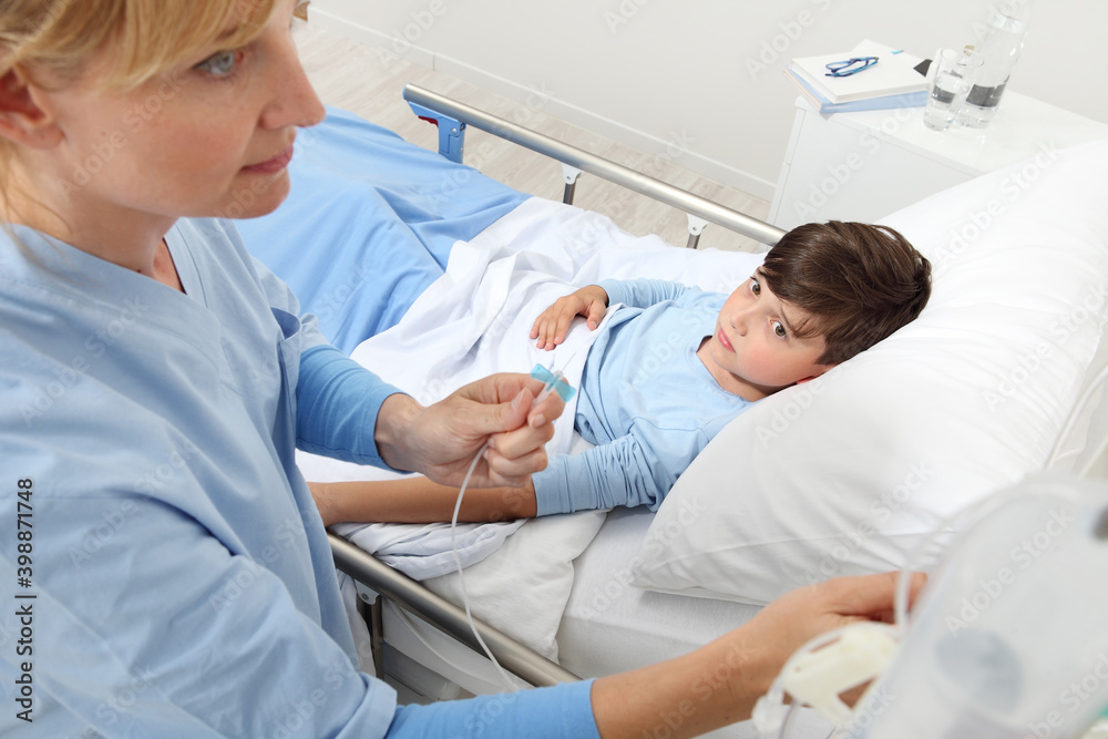 Up view of nurse checking the drip with sick child lying in bed next to her in hospital room Up view of nurse checking the drip with sick child lying in bed next to her in hospital room