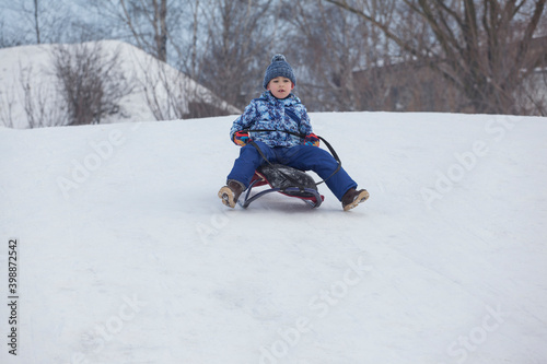 little boy riding from a slide on a sleigh