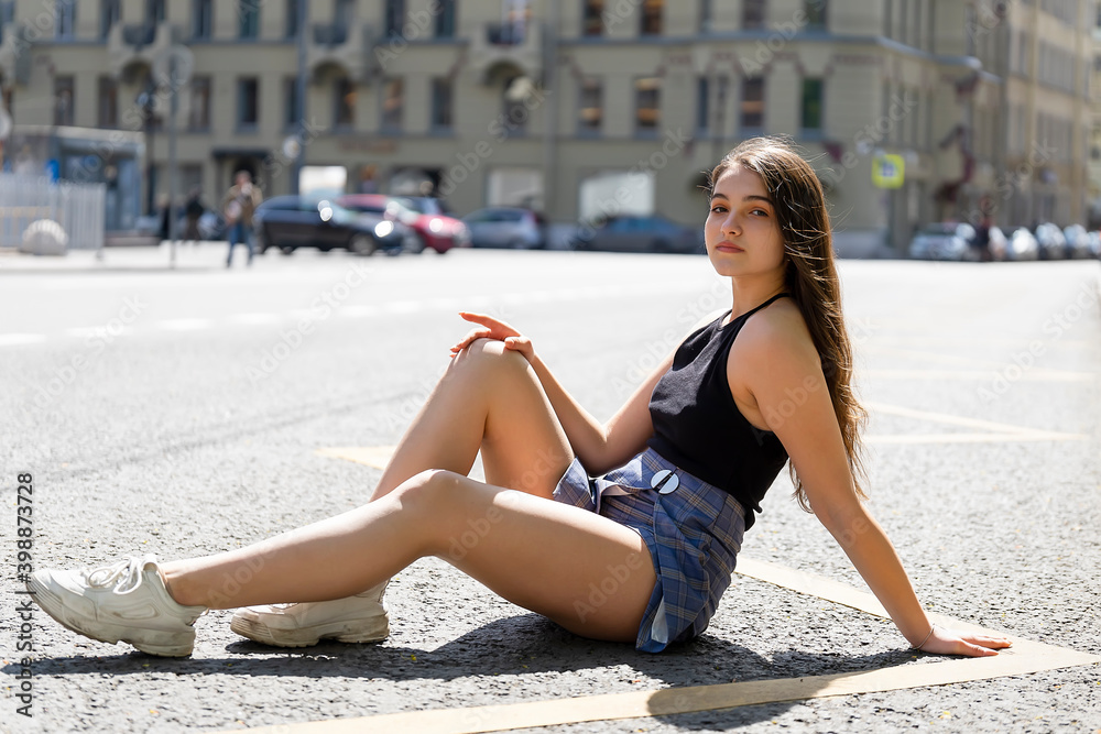 Young beautiful woman sitting in the city on the road on the asphalt