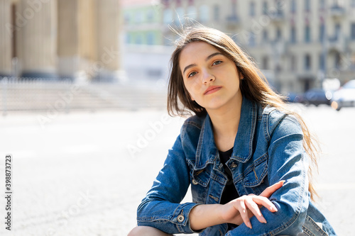 Young beautiful woman sitting in the city on the road on the asphalt