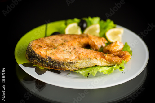 piece of fried salmon fish in a plate with lemon