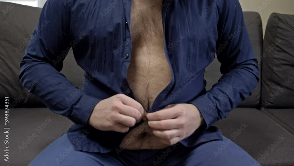 Overweight man tries unsuccessfully to button his shirt. Overweight problem.