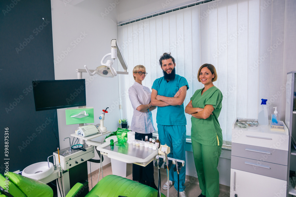Fototapeta premium Team of three happy dentists proudly posing in a dental office