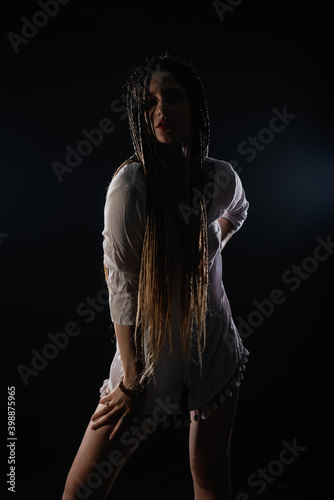 Attractive female feminist waring tribal short white dress. The isolated photo on a black background. Woman queen concept.
