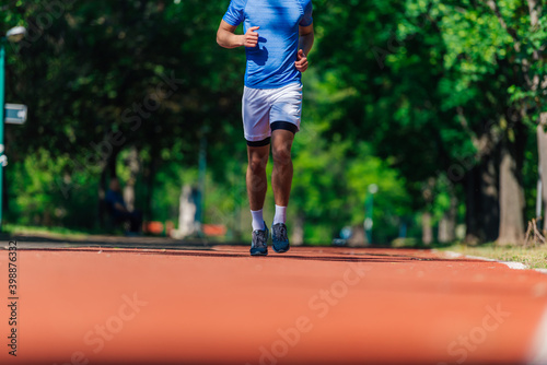 Close up feet with running shoes and strong athletic legs of sport man jogging on the running track