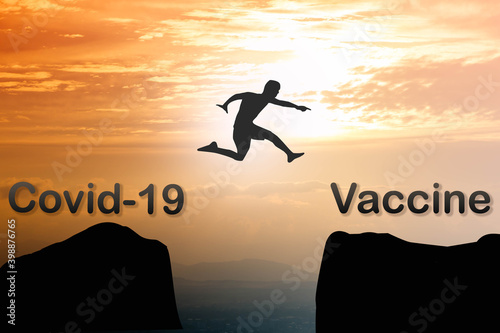 Silhouette man jumping from covid-19 to vaccine on beautiful gold sky at sunset over mountain