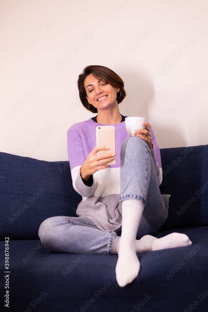 Caucasian cute woman blogger at home in warm purple sweater pullover take selfie in on mobile phone for social media content in apartment Caucasian cute woman blogger at home in warm purple sweater pullover take selfie in on mobile phone for social media content in apartment