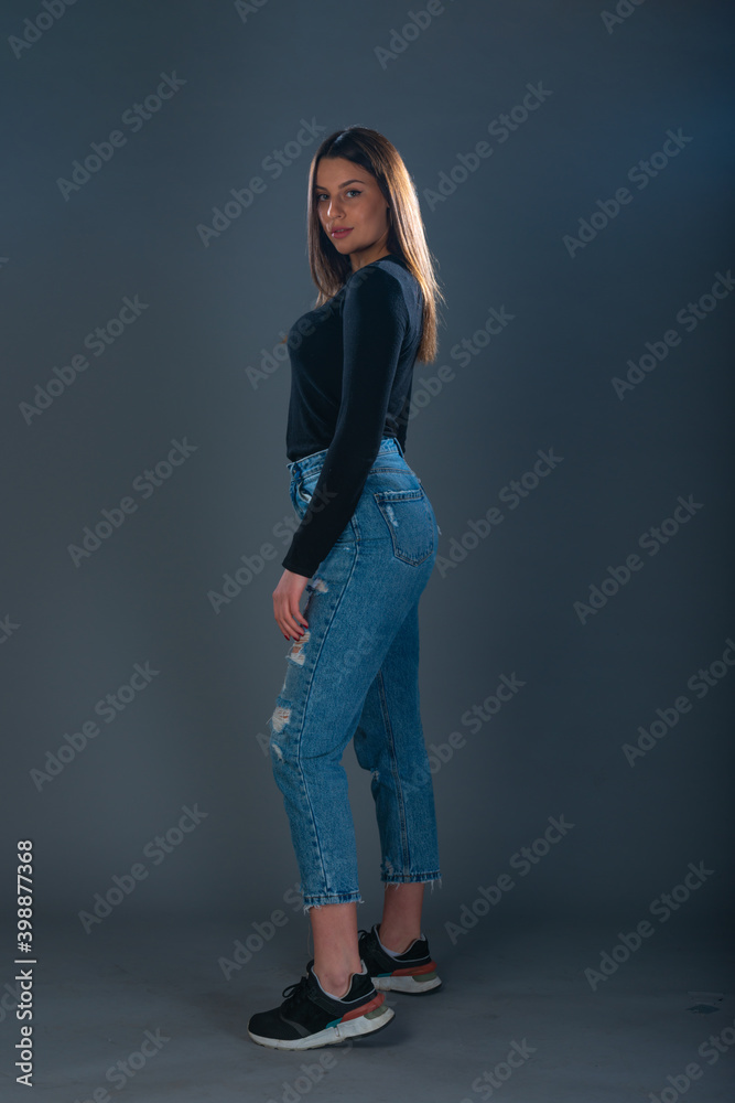 Beautiful young female model in jeans on dark background Beautiful young female model in jeans on dark background