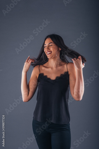 Female model dressed in black is posing in a studio