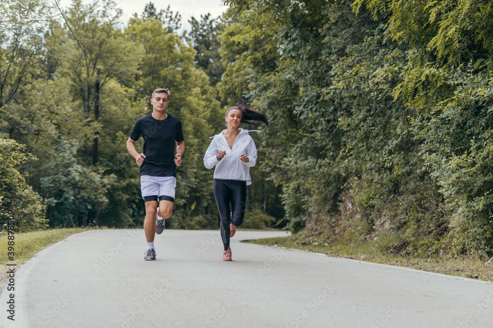 Athletic couple running on a street next to each other. Nature,fit and healthy concept. Athletic couple running on a street next to each other. Nature,fit and healthy concept.