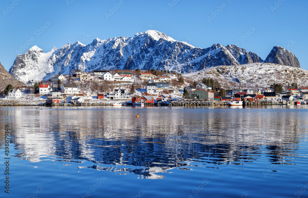 Lofoten islands, Norway. Scenic winter landscape with fishing village and showy mountains reflected on water. 