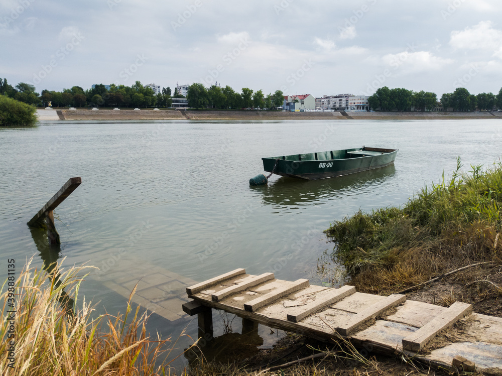 Landscape of Sava river with flooded wooden dock and moored fishing boat in Bosanski Brod, Bosnia and Herzegovina during gloomy summer morning Landscape of Sava river with flooded wooden dock and moored fishing boat in Bosanski Brod, Bosnia and Herzegovina during gloomy summer morning