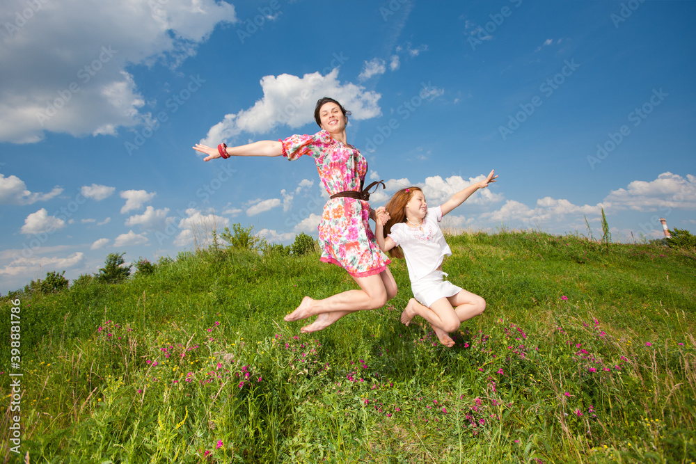 Redhead mom and redhead daughter jump on a green field Redhead mom and redhead daughter jump on a green field
