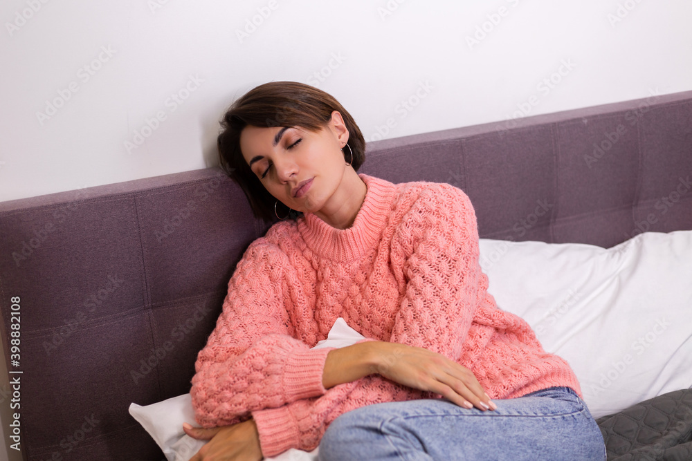 Caucasian pretty woman in pink cute knitted pullover resing at home in bed, smiling, enjoying time alone, hugging pillow. Caucasian pretty woman in pink cute knitted pullover resing at home in bed, smiling, enjoying time alone, hugging pillow.