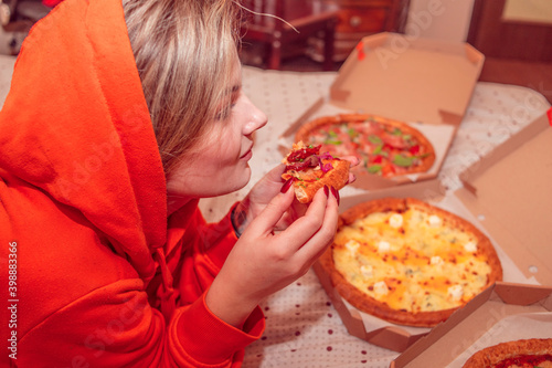 Girl eating pizza while lying on the bed