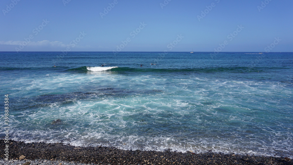 Seashore of Playa de Las Americas, Tenerife, Canary Islands, Spain, waves in the ocean on a sunny summer day. 