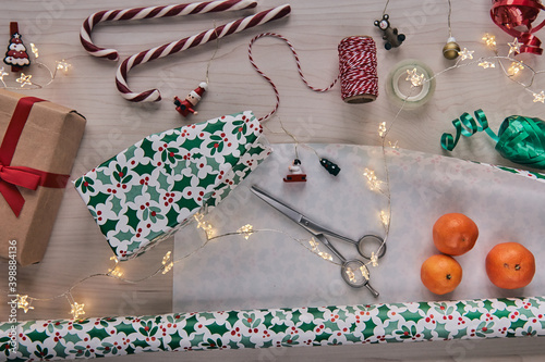 Christmas composition. Giftboxes, presents wrapping with paper and ribbon, lights, candy canes on wooden background. Holdiay DIY handmade home decoration. Winter, new year Flat lay, top view. photo