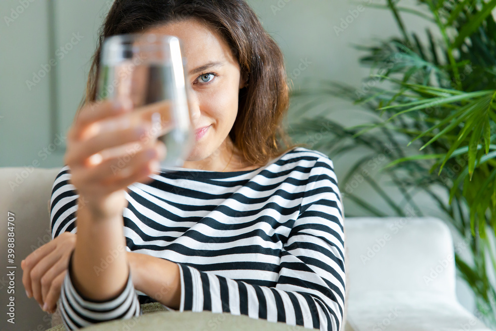 Young woman smiling while looking at the camera through the glass of water Young woman smiling while looking at the camera through the glass of water