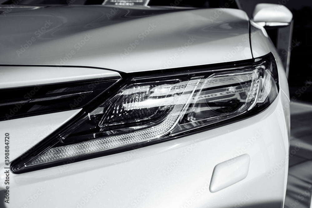 headlight of modern prestigious white car close up. Close up photo of modern car, detail of headlight. Headlight car Projector LED of a modern luxury technology and auto detail.