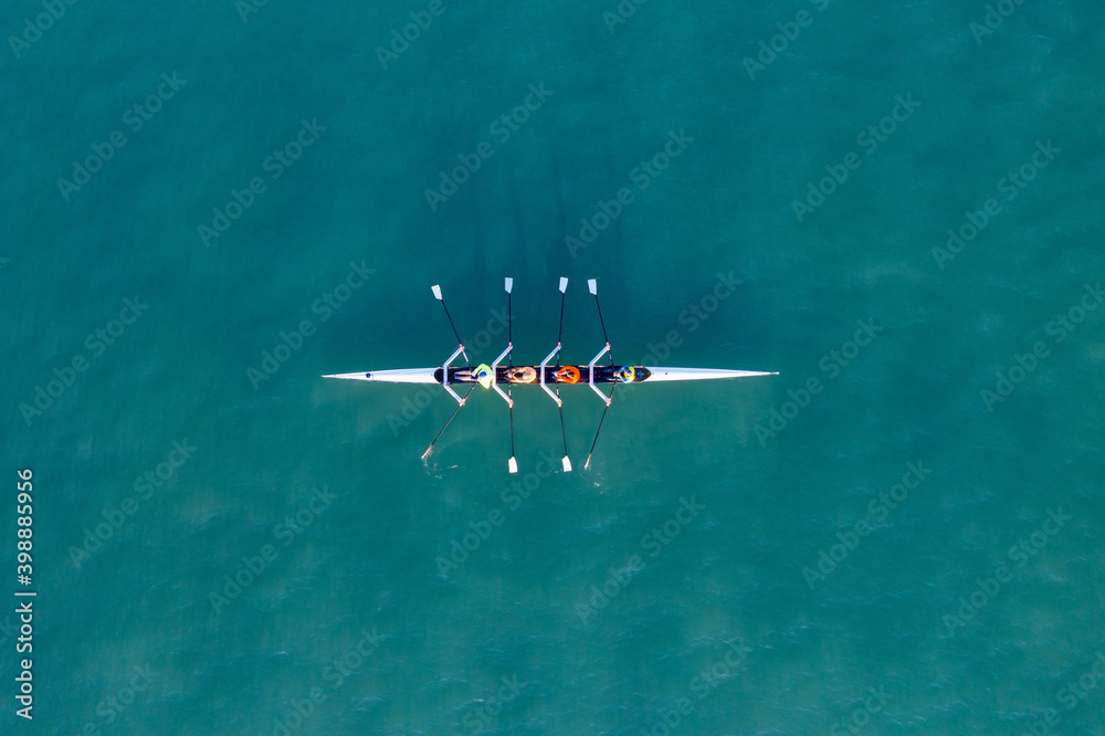 Sport Canoe with a team of four people rowing on tranquil water, Aerial view. - obrazy, fototapety, plakaty 