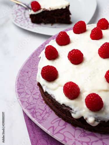 Delicious chocolate cake with cheese cream on top and raspberries. Christmas cake. Selective focus. Copy space.