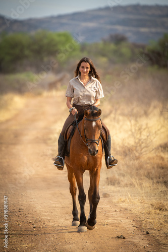 Brunette smiles riding horse along dirt track