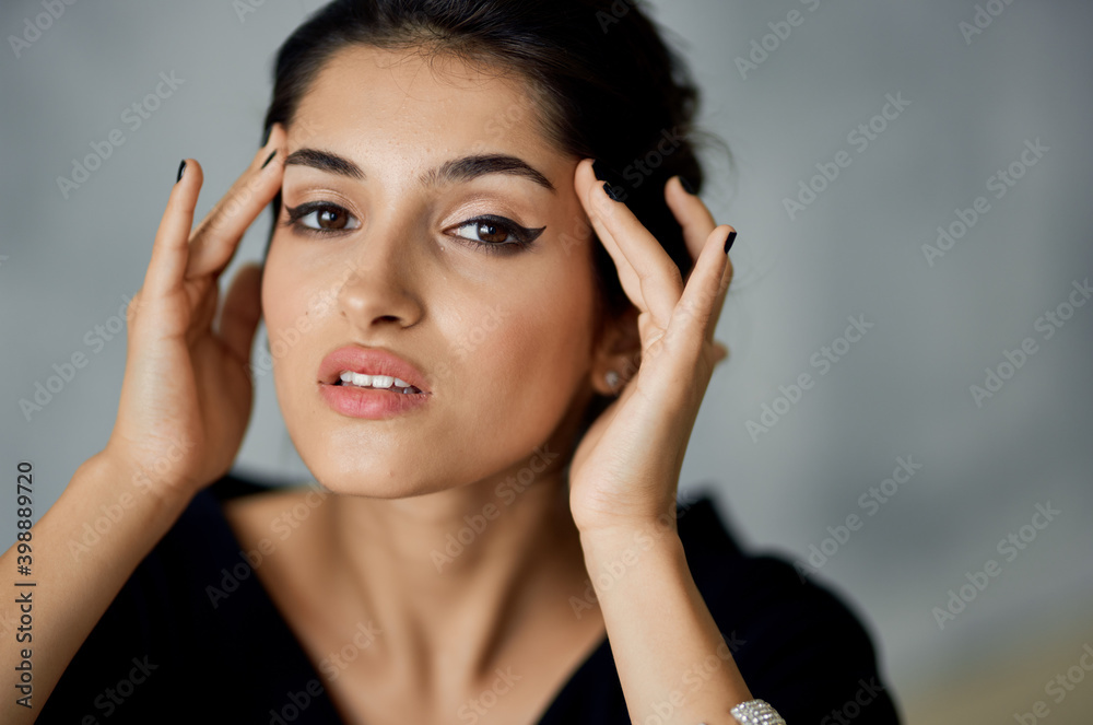 beautiful woman model touches her face with her hands on a gray background and evening dress decoration on her hand beautiful woman model touches her face with her hands on a gray background and evening dress decoration on her hand