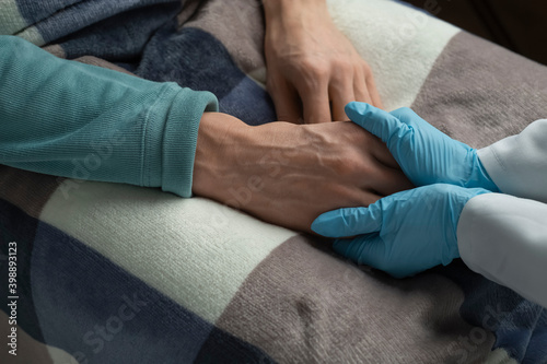 The nurse supports the patient by holding a gloved hand.