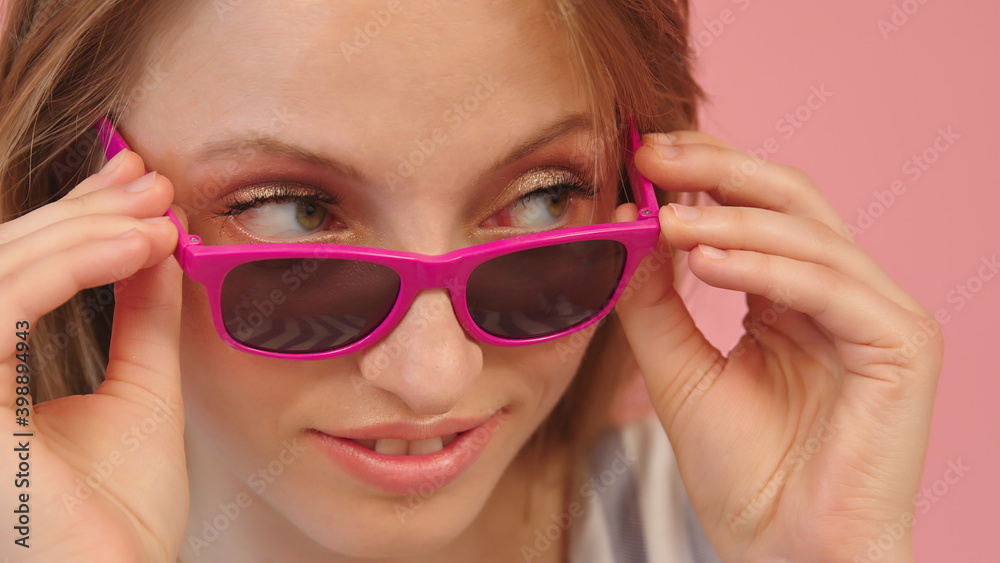 Portrait of young caucasian woman looking over the pink sunglasses. High quality photo Portrait of young caucasian woman looking over the pink sunglasses. High quality photo
