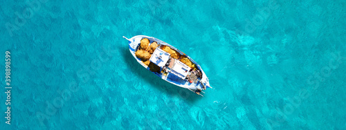 Aerial drone top view ultra wide panoramic photo of traditional wooden fishing boat anchored in crystal clear turquoise sea of Antipaxos island, Ionian sea, Greece