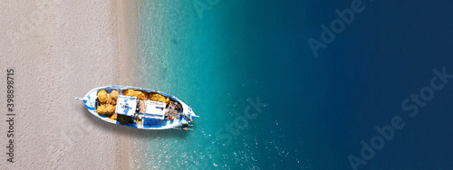 Aerial top view photo of traditional fishing boat anchored in turqoise bay and beach of Balos, Chania, Crete, Greece