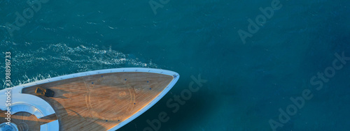 Aerial drone ultra wide top down photo of luxury exotic yacht nose with wooden deck anchored in paradise turquoise bay