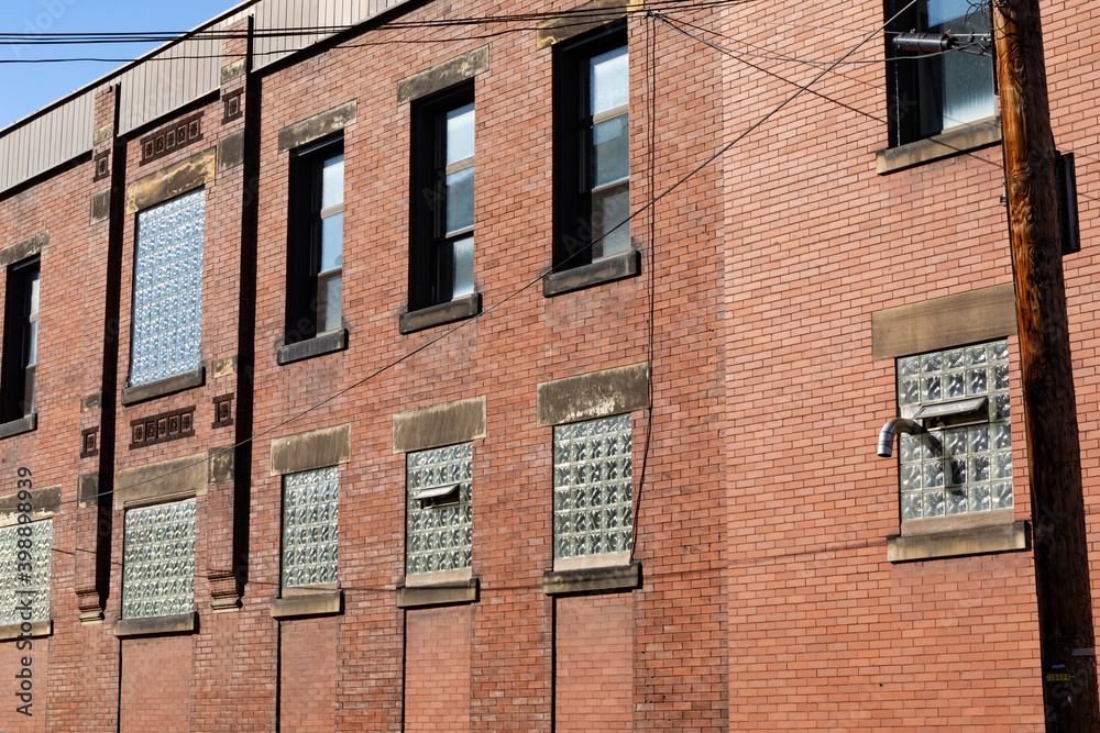 Angled view of old red brick industrial building, lower windows filled with glass block, interesting architectural details, horizontal aspect Angled view of old red brick industrial building, lower windows filled with glass block, interesting architectural details, horizontal aspect