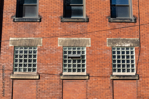 Red brick old commercial industrial building, lower windows with glass brick, architectural details, horizontal aspect