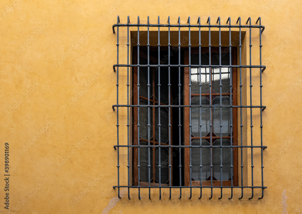 Big window with iron grill, in a yellow wall