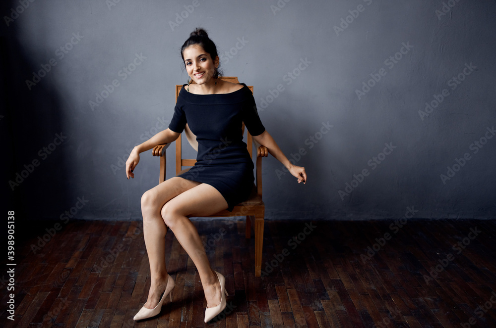 pretty woman sitting on a chair in a black dress room gray wall model hairstyle pretty woman sitting on a chair in a black dress room gray wall model hairstyle