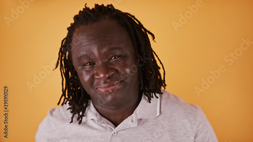 Portrait of young african american black man with braided hair isolated over orange background. High quality photo