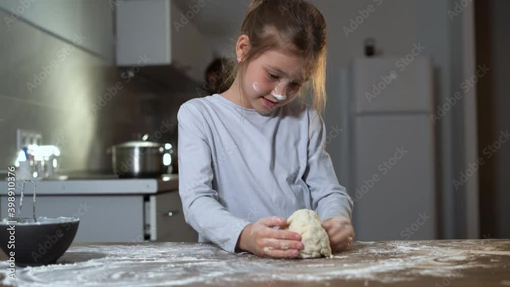a Caucasian-looking girl is standing in the kitchen and kneading dough. home cooking concept. a Caucasian-looking girl is standing in the kitchen and kneading dough. home cooking concept.