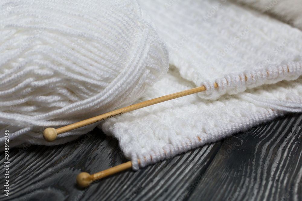 Knitting with needles. Wooden knitting needles and white threads. On black pine boards. Knitting with needles. Wooden knitting needles and white threads. On black pine boards.