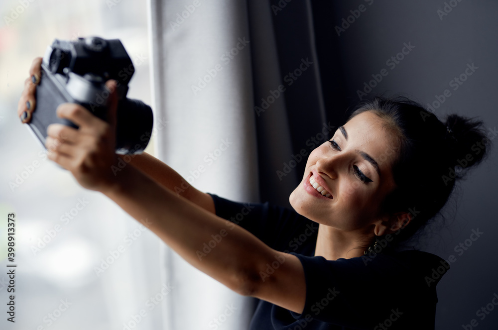 happy woman with photo camera indoors with window in the background happy woman with photo camera indoors with window in the background