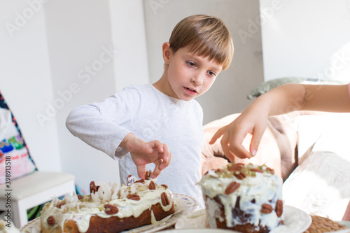 Cheerful boy in white clothes cooking pie on white background