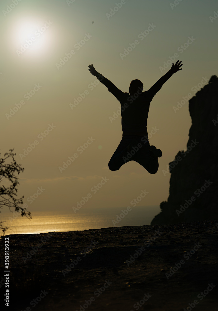 silhouette of a jumping man on the sunset shore