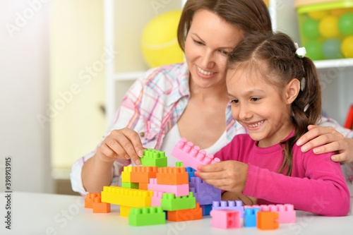 Portrait of little daughter and mother playing